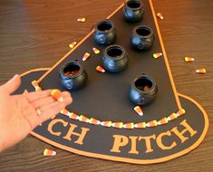 a hand reaching for candy in front of a witch's hat shaped trick board