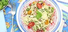 a pasta salad with tomatoes, spinach and mushrooms on a blue and white plate