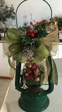 a green lantern with pine cones, berries and bells on it sitting on a counter