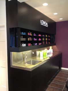 a store counter with lots of bottles on it's shelves and lights above the sink