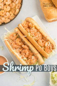 two shrimp po boys are on a plate next to some dipping sauce and bread rolls