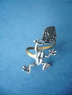 a silver frog sitting on top of a blue surface next to a gold band ring