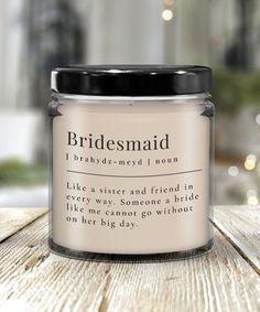 a candle that says bridesmaid on it sitting on top of a wooden table