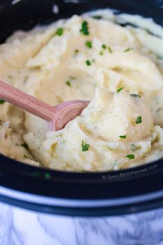 mashed potatoes in a crock pot with a wooden spoon