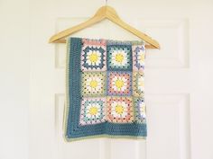 a crocheted granny blanket hanging on a door hanger with a wooden hook