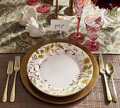 a table set with plates, silverware and flowers