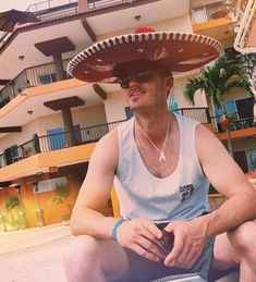 a man wearing a sombrero sitting on the ground