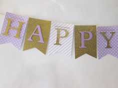 a happy birthday banner with purple and gold glitter letters on it, hanging from a string