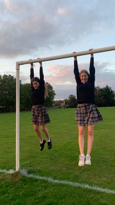 two girls are hanging from a soccer goal