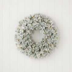 a white wreath hanging on the wall with snow flakes all over it and lights