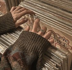 a person's hand on top of an old record player in front of a stack of records