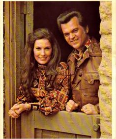 a man and woman standing next to each other on a window sill