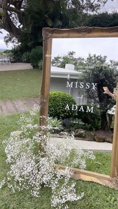 a mirror sitting on top of a grass covered field next to a tree and white flowers