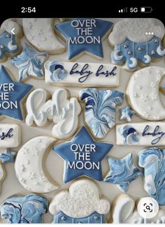 cookies decorated with blue and white icing are arranged in the shape of moon, stars, and crescents