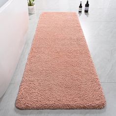 a pink rug on the floor next to a bath tub