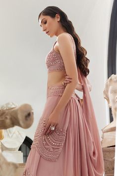 Blush pink pre-draped, lehenga saree with scallop detailing and highlighted with pearls, crystal embroidery. Paired with a padded blouse with all over sequins, thread, pearls and crystal work.
Components: 2
Pattern: Embroidery, Embellished
Type Of Work: Scallop, Thread, Beads, Sequins, Pearl, Crystal
Neckline: Scoop Neck
Sleeve Type: Sleeveless
Fabric: Flat Chiffon and Organza
Color: Pink
Other Details: 
Model height: 5 ft 7 inches, wearing size XS
Blouse:
Padded

Occasion: Destination Wedding - Elegant Side Open Georgette Choli, Wedding Pre-draped Saree With Mirror Work, Draped Georgette Designer Lehenga, Draped Semi-stitched Lehenga With Sheer Dupatta, Elegant Side Open Unstitched Choli Blouse, Elegant Unstitched Side Open Choli, Elegant Side Open Unstitched Choli, Elegant Unstitched Side-open Choli, Elegant Side Open Lehenga For Reception