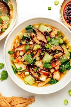 two bowls filled with soup and vegetables on top of a table