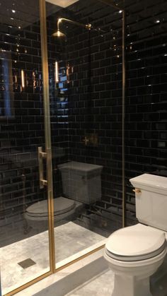 a white toilet sitting inside of a bathroom next to a walk in glass shower door