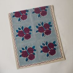 a piece of cloth with flowers on it sitting on top of a white tablecloth