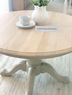 a white vase with flowers sitting on top of a table next to a cup and saucer