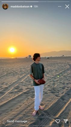 a man standing in the sand holding a football