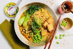 a bowl filled with noodles and vegetables next to chopsticks on top of a table