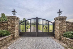 an image of a gated driveway with stone walls and iron gates on both sides