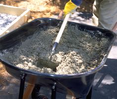 a person shoveling sand into a wheelbarrow