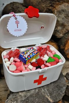 a white container filled with candy and candies on top of a wooden table next to rocks