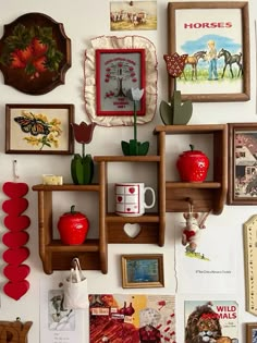 the wall is covered with many different pictures and framed art pieces, including red apples