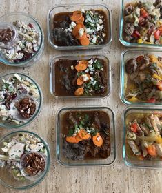 six glass containers filled with food on top of a wooden table next to each other