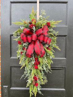 a red and green wreath hanging on the front door