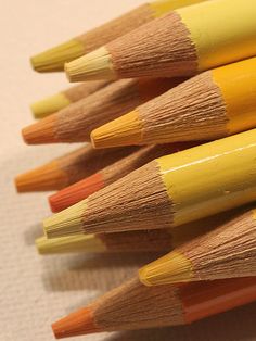 several yellow and orange pencils lined up together