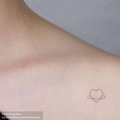 a small heart tattoo on the back of a woman's left shoulder and chest