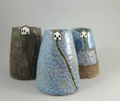 three small vases with houses on them