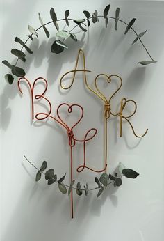 three metal letters are arranged in the shape of hearts and leaves on a white surface