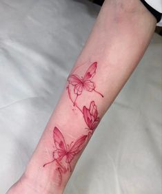 a woman's arm with red ink on it that has three butterflies flying around