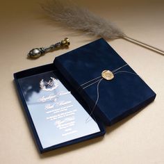 a blue wedding card box with a feather on the table next to it and a pen