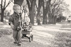 two young boys pushing a wagon in the park