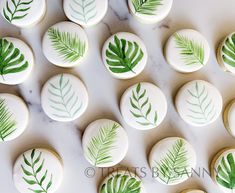 decorated cookies with green leaves on them sitting on a marble counter top, ready to be eaten