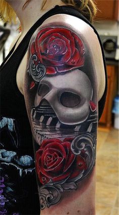 a woman's arm with a skull and roses on it, as well as a red rose