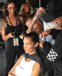 a woman getting her hair cut by a man in front of other people at an event