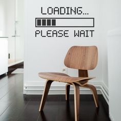 a chair sitting in front of a wall that says loading please wait