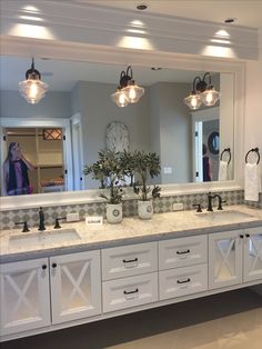 a large bathroom with double sinks and mirrors on the wall, along with lights above them