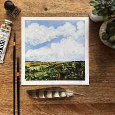 a painting on a table next to some paintbrushes and an inking pen