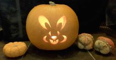 a pumpkin carved to look like a face with eyes and ears on it, surrounded by other pumpkins