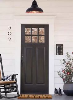 a rocking chair sitting in front of a black door with numbers on the side wall