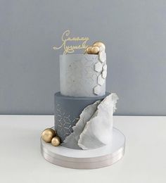 a three tiered cake with gold and silver decorations