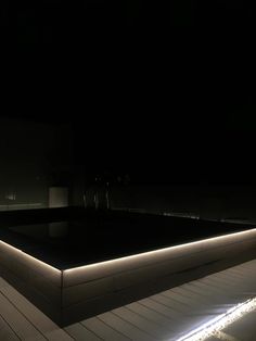 an illuminated pool at night with lights on the floor and in the background is a dark sky