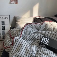 an unmade bed with a book on it next to pictures and other things in the background